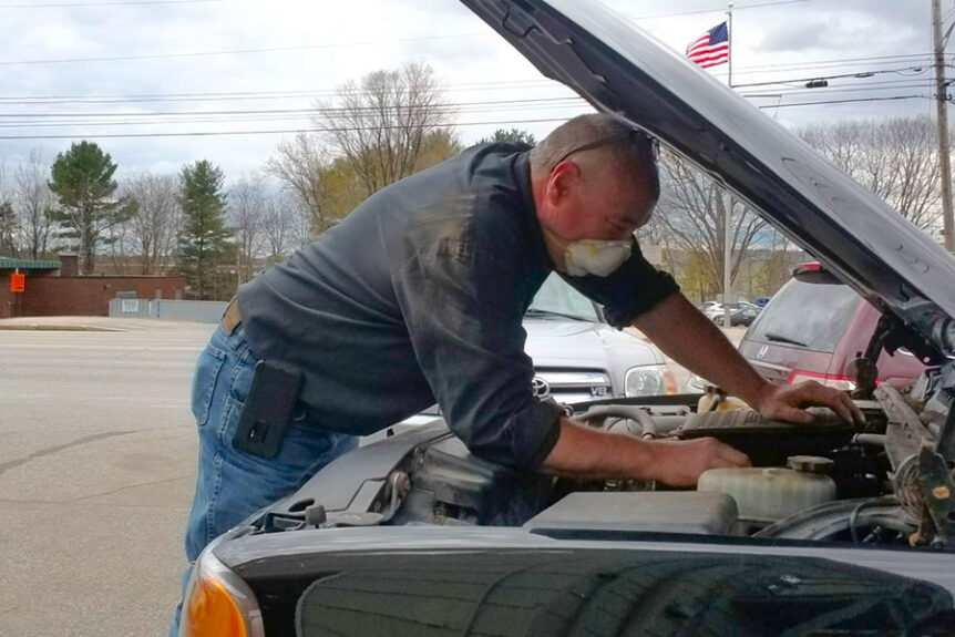 mechanic working under hood of vehicle maine auto repair